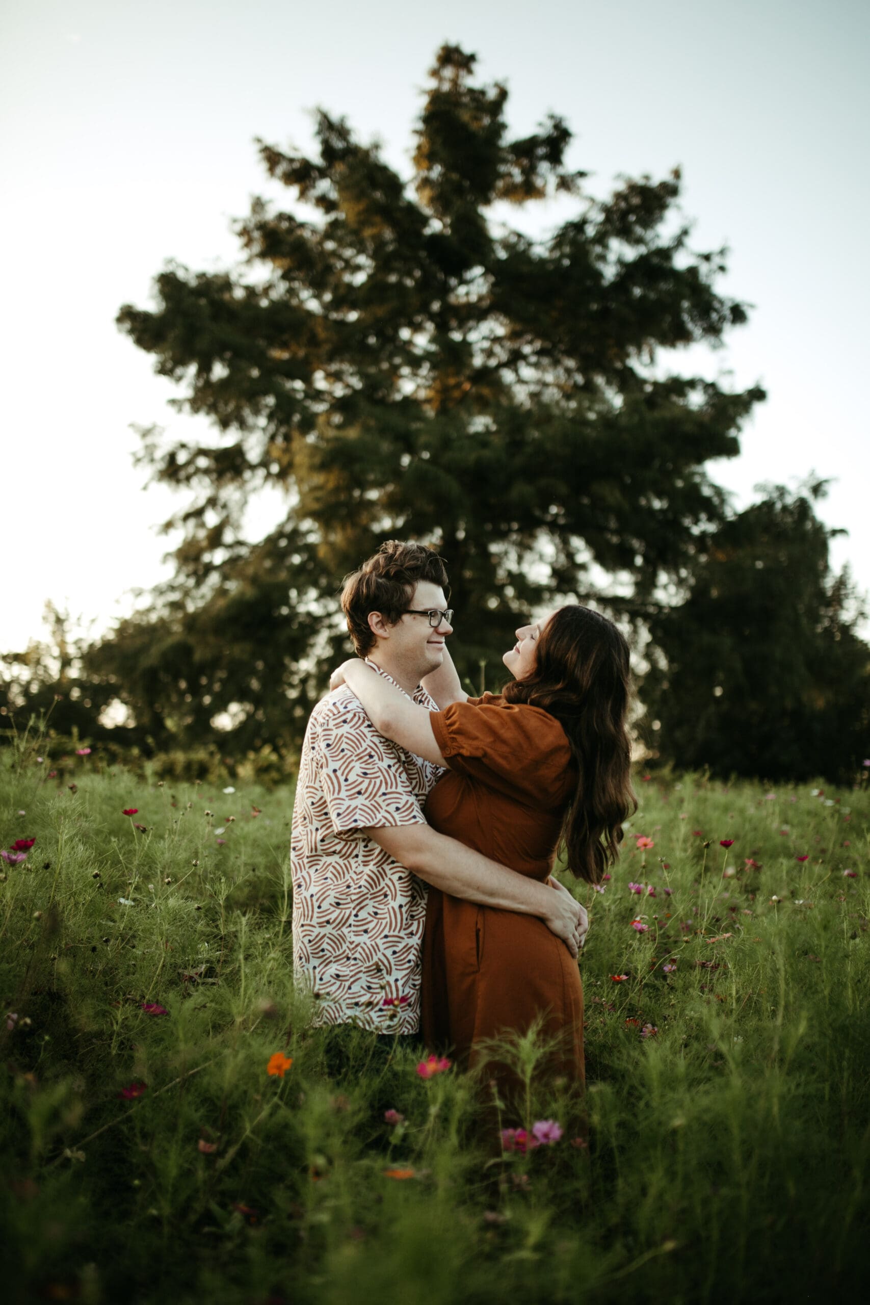 couple in wildflower field in nature at a winery, burnt orange dress, patterned shirt