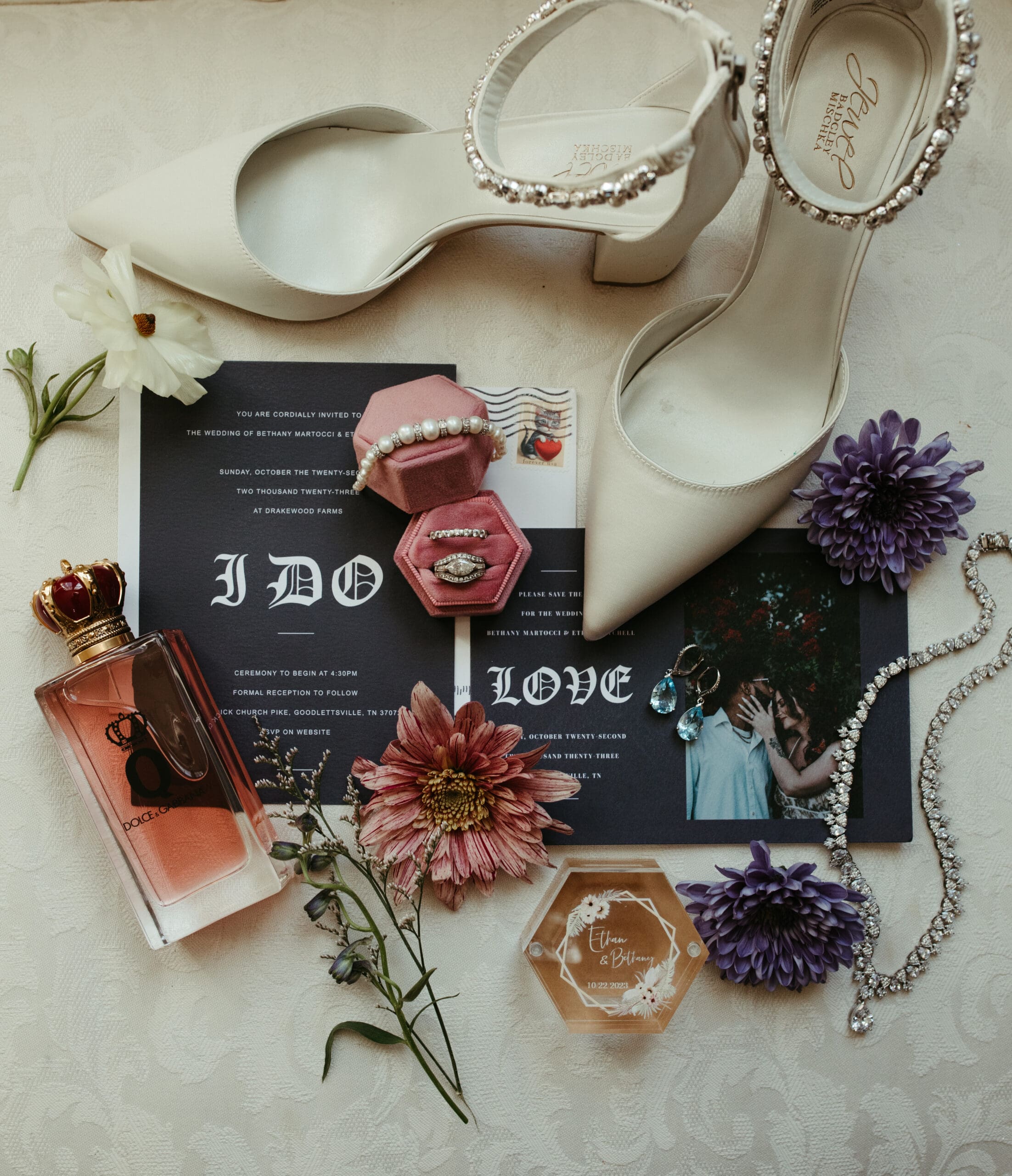 detailed invititaion with rings, perfume, bridal shoes and loose flowers at drakewood farm